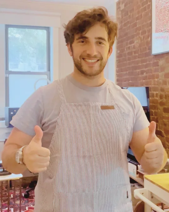 A Hanee community member wearing a striped apron and giving two thumbs up