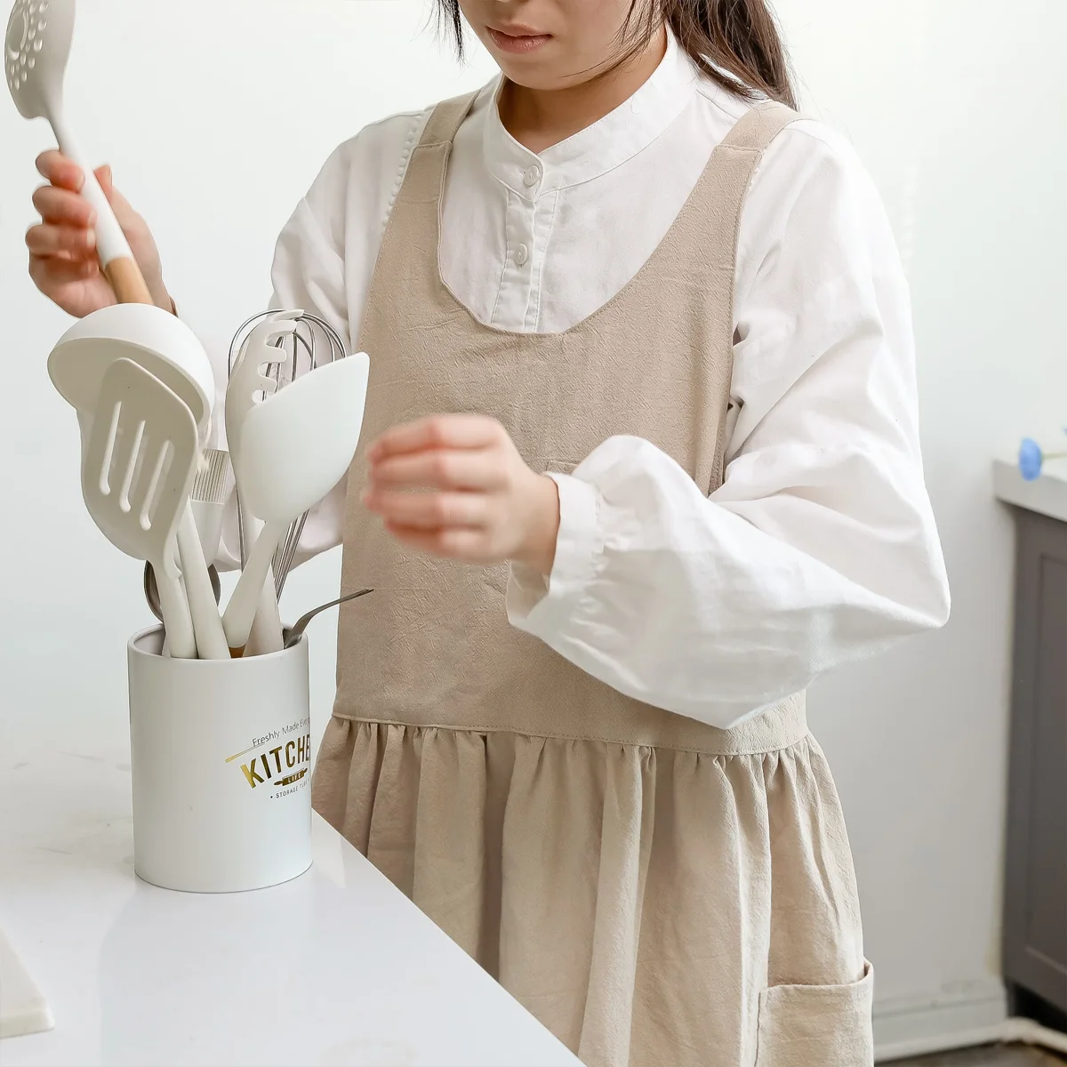 A gathered Hanee cotton pinafore worn over everyday clothing