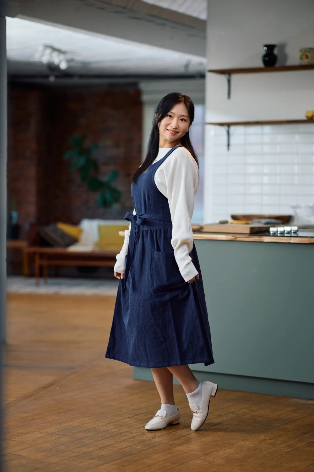 Woman wearing Hanee's navy linen-blend pinafore apron with a gathered waist